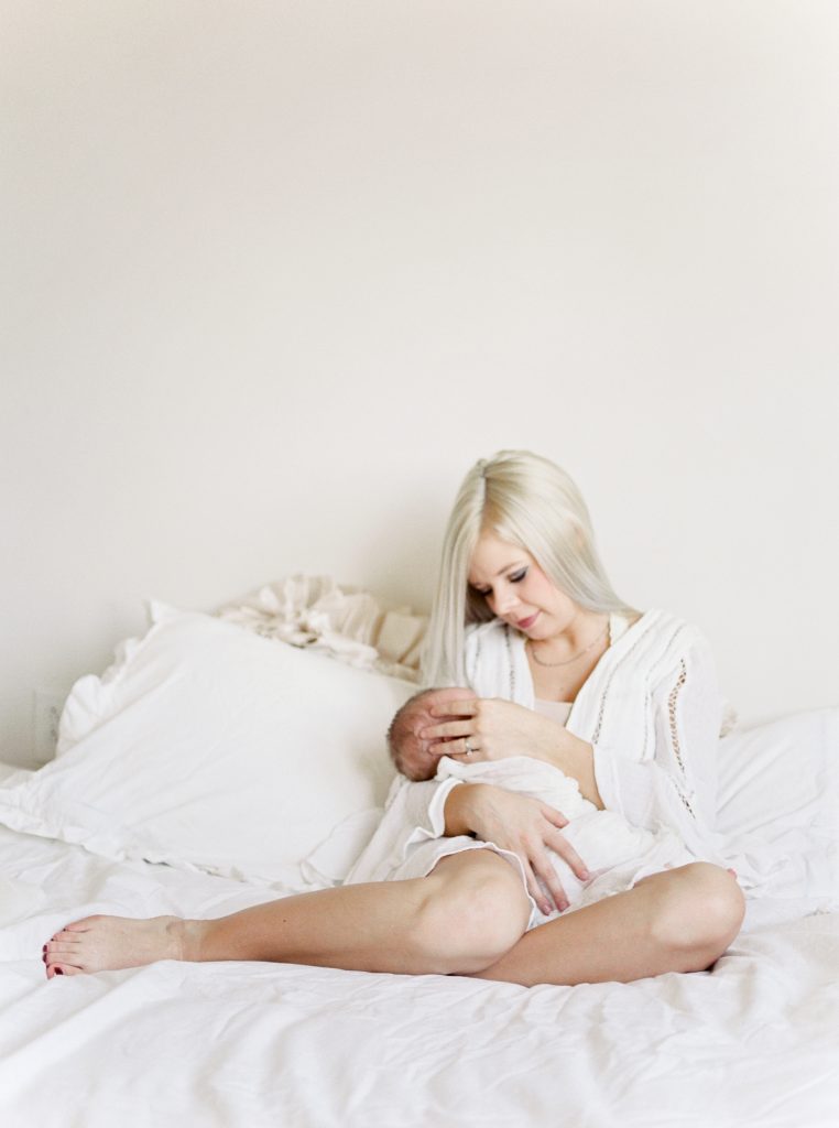 a woman and her baby are sitting on a bed with white bedding