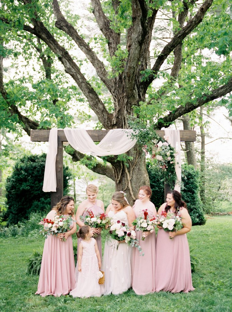 bride and her bridesmaids under the arbor at her Greencloft Club wedding in charlottesville VA