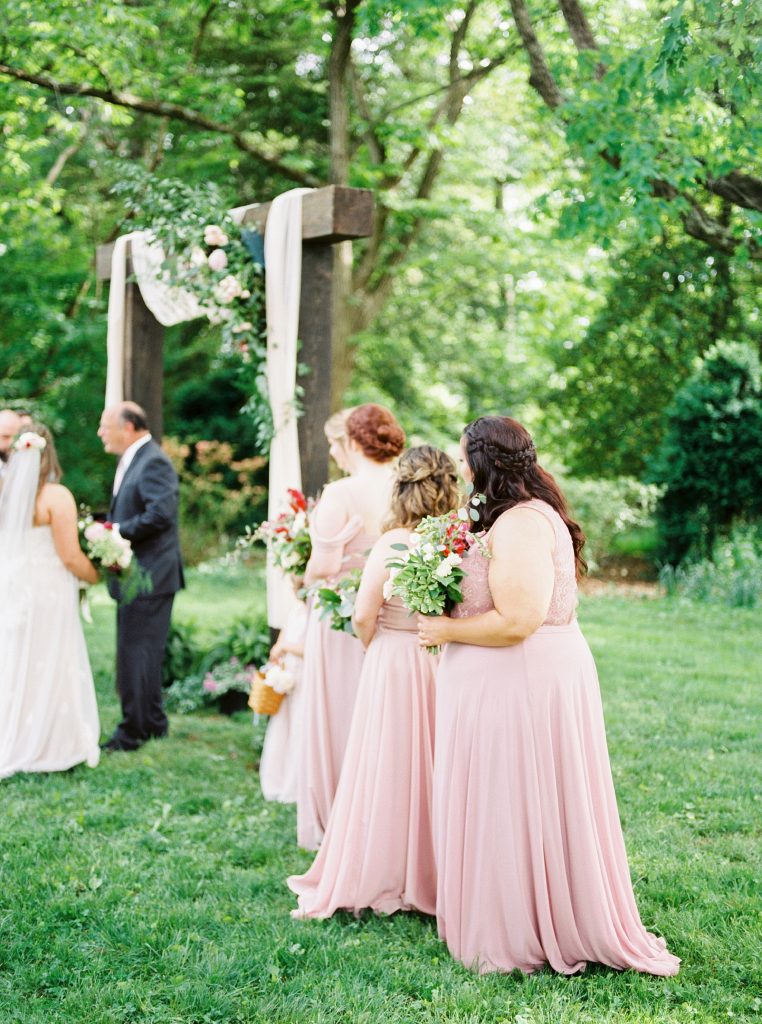 bridesmaids dressed in blush and mauve standing during the ceremony in charlottesville va